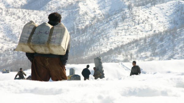 صفی از کولبران در منطقه‌ای کوهستانی با انبوهی برف