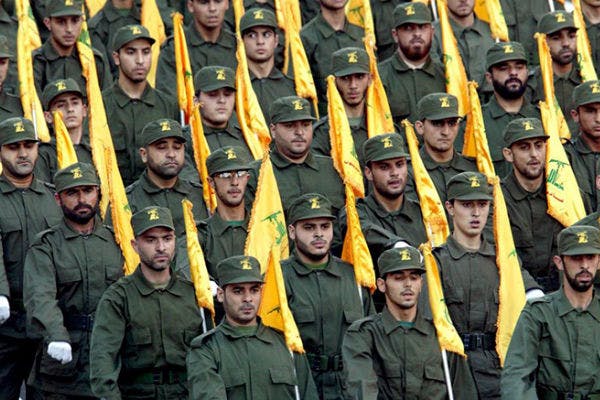 گروهی از سربازان حزب‌الله لبنان با لباس سبز خاکی و پرچمهای زردرنگ حزب‌الله لبنان