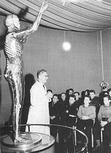 کارمند موزه بهداشت، مجسمه زن شیشه‌ای را برای نوجوانان بازدید کننده، توضییح می‌دهد ۱۹۵۸