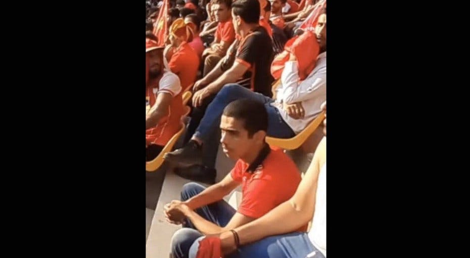 محسن محمدپور با لباس قرمز در ورزشگاه در حال تماشای فوتبال