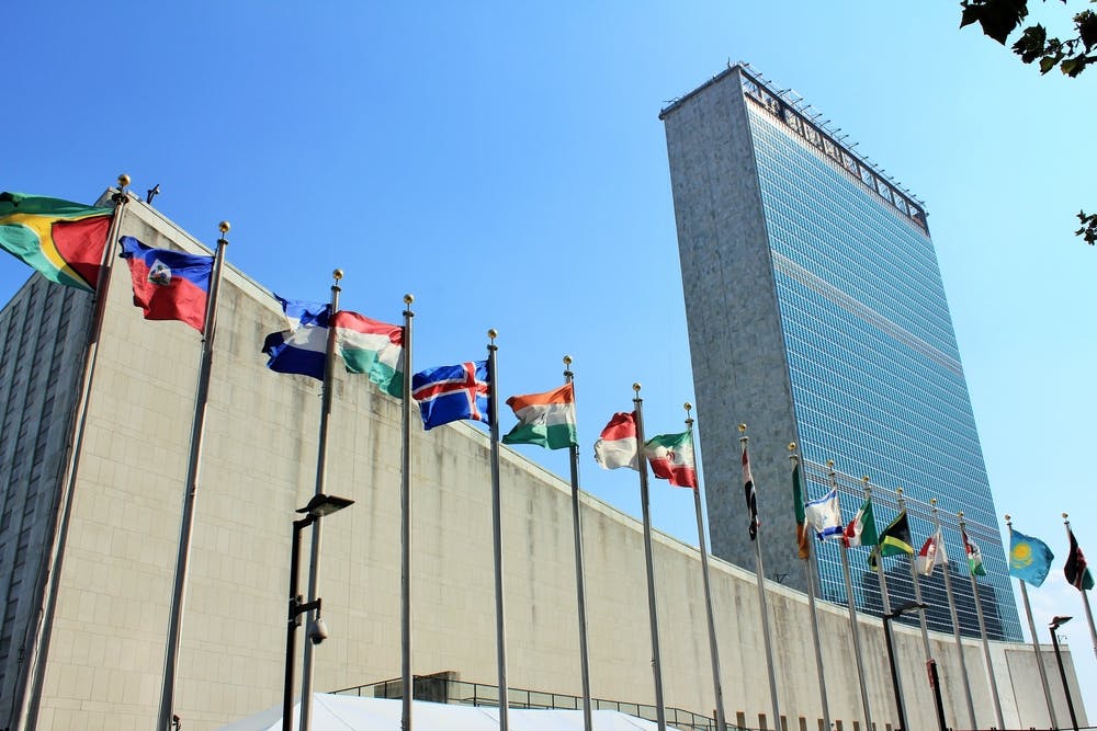 ساختمان سازمان ملل در نیویورک و ردیف پرچم‌ها در برابر آن