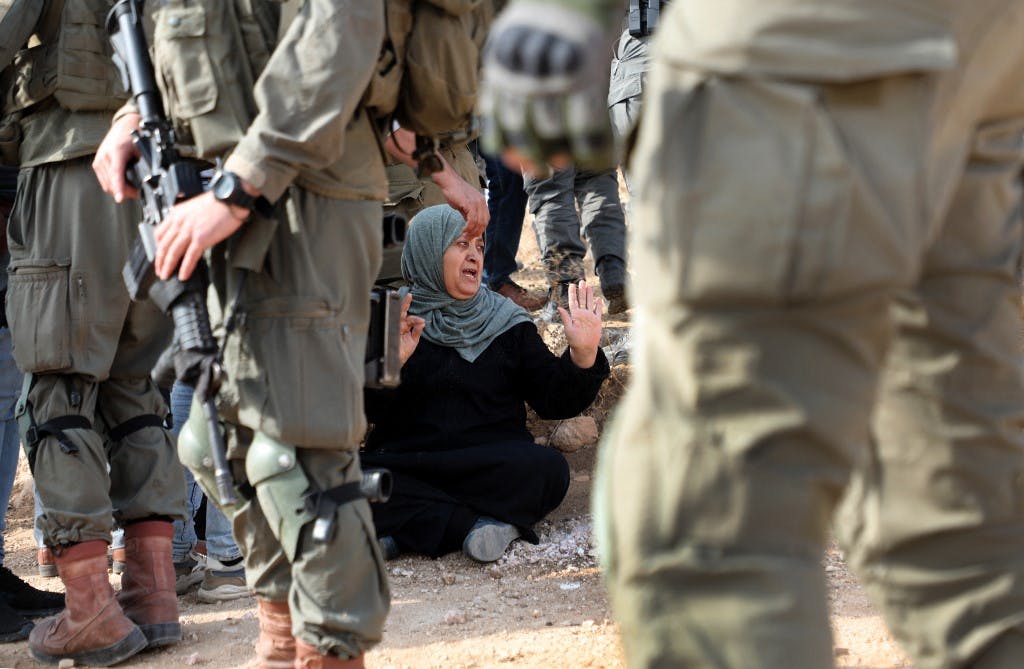 یک زن فلسطینی مقابل نیروهای اسرائیلی که خانه‌ای متعلق به فلسطینی ها را در روستای بنی نعیم در کرانه باختری تخریب می‌کنند، تحصن کرده است. تاريخ عکس: ۲۵ اکتبر ۲۰۲۲