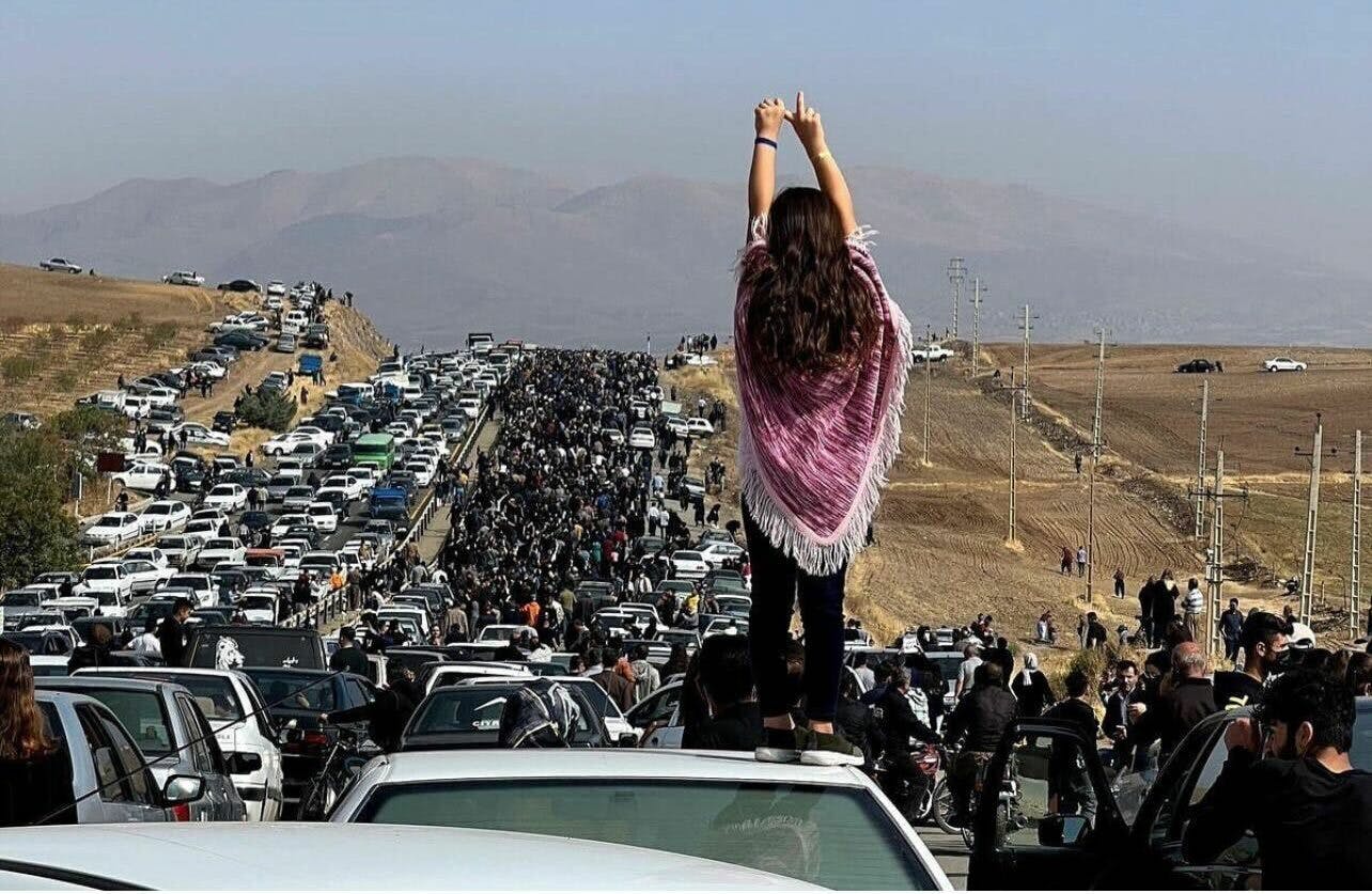 سقز، چهلم ژینا (مهسا) امینی. زنی ایستاده بر سقف خودرو دست‌هایش را به نشانه پیروزی بالا برده است.