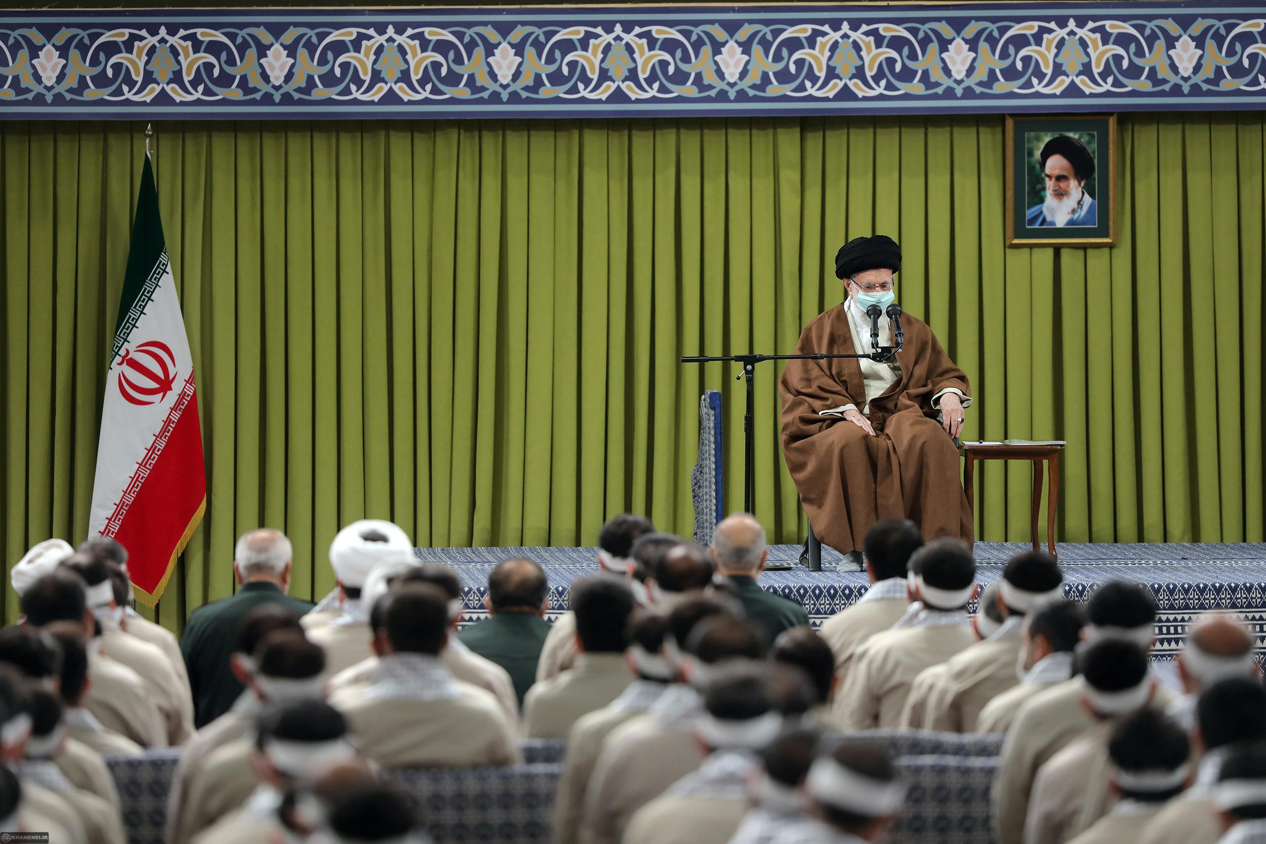 علی خامنه‌ای نشسته بر صندلی در مقابل گروهی از بسیجی‌ها در حسینیه رهبر جمهوری اسلامی