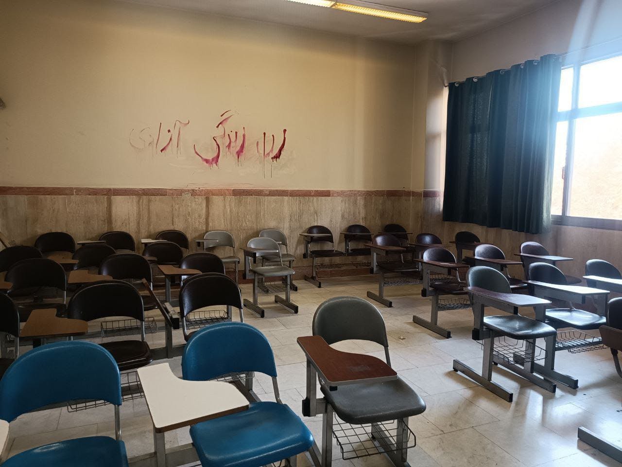 یک کلاس خالی با دیوارنویس سرخ‌رنگ زن، زندگی، آزادی