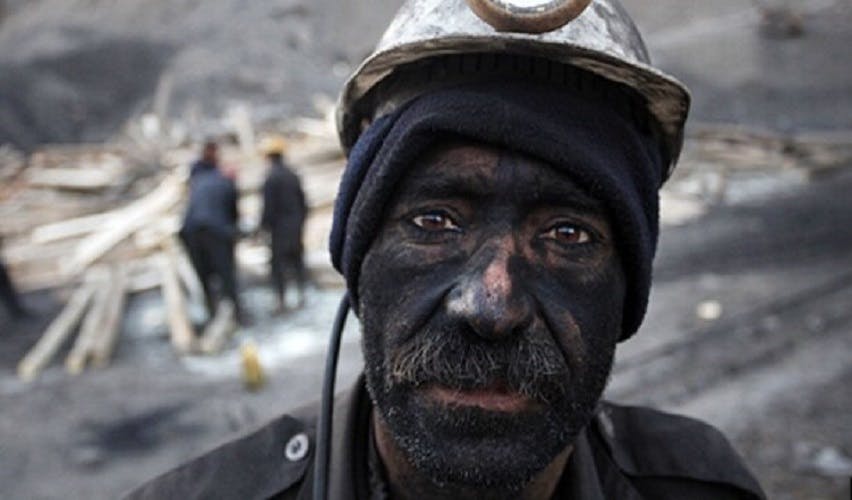 یک کارگر معدن با چهره‌ای خسته و پوشیده از زغال.