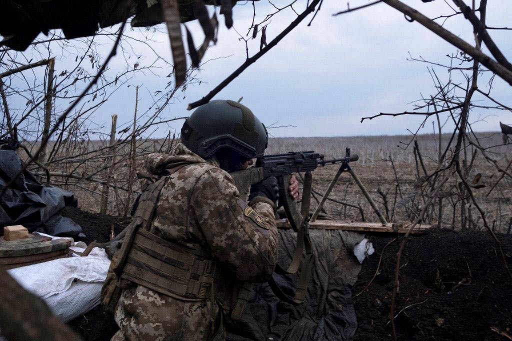 یک سرباز داوطلب ارتش اوکراین سلاح در دست دارد و در سنگر نشسته و روبه‌روی خود را هدف گرفته است.
