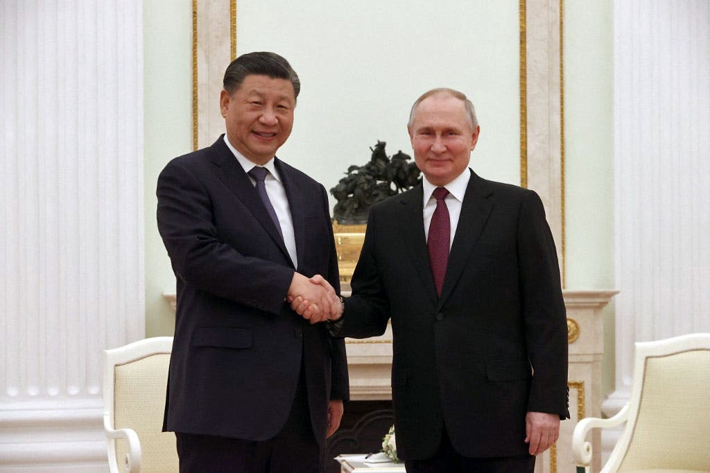 در تصویر ولادیمیر پوتین، رئیس جمهوری روسیه دست شی جین پینگ، رئیس جمهوری چین را می‌فشارد و هر دو رو به دوربین می‌خندند.