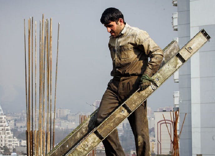 کارگران منتظر تعیین حداقل دستمزد مانده‌اند. یک کارگر ساختمانی در حال حمل آهن.