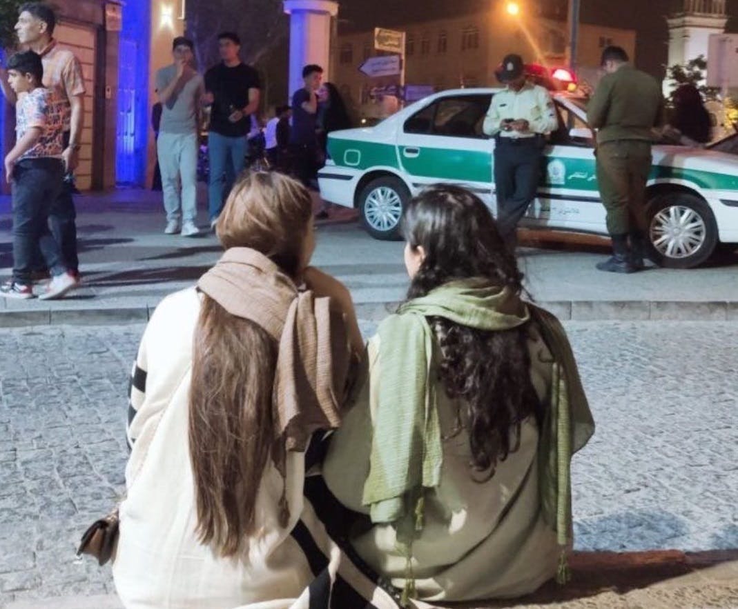 دو دختر جوان مقابل یک خودروی پلیس حجاب از سر برداشته اند
