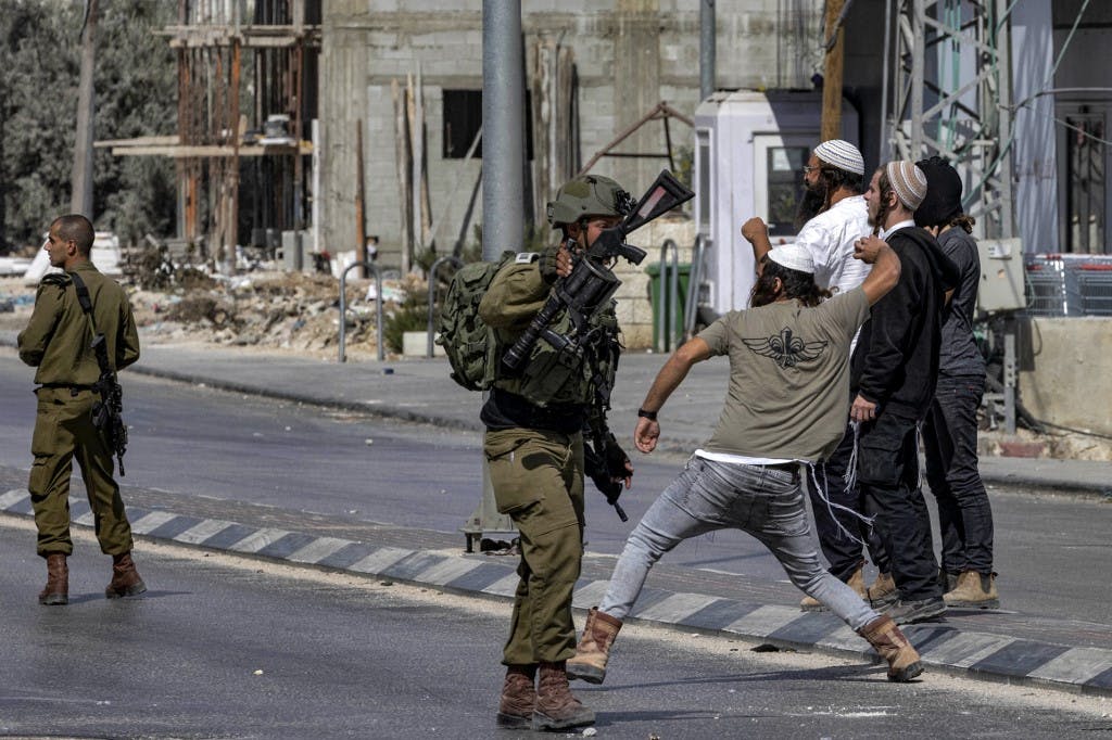 سربازان اسرائیلی در کنار شهرک‌نشین‌هایی که به سمت فلسطینیان حواره در اکتبر ۲۰۲۲ سنگ پرتاب می‌کنند ــ عکس: Oren ZIV / AFP