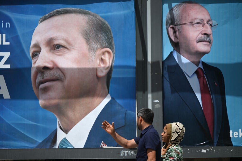 زن و شوهری از کنار بیلبوردهایی با پرتره رجب طیب اردوغان، رئیس جمهور ترکیه (سمت چپ) و رهبر حزب جمهوری خواه خلق (CHP) و نامزد ریاست جمهوری، کمال قیلیچداراوغلو (سمت راست) در سانلیورفا، جنوب شرقی ترکیه در ۲۸ آوریل ۲۰۲۳ عبور می کنند. (عکس از OZAN KOSE / AFP)