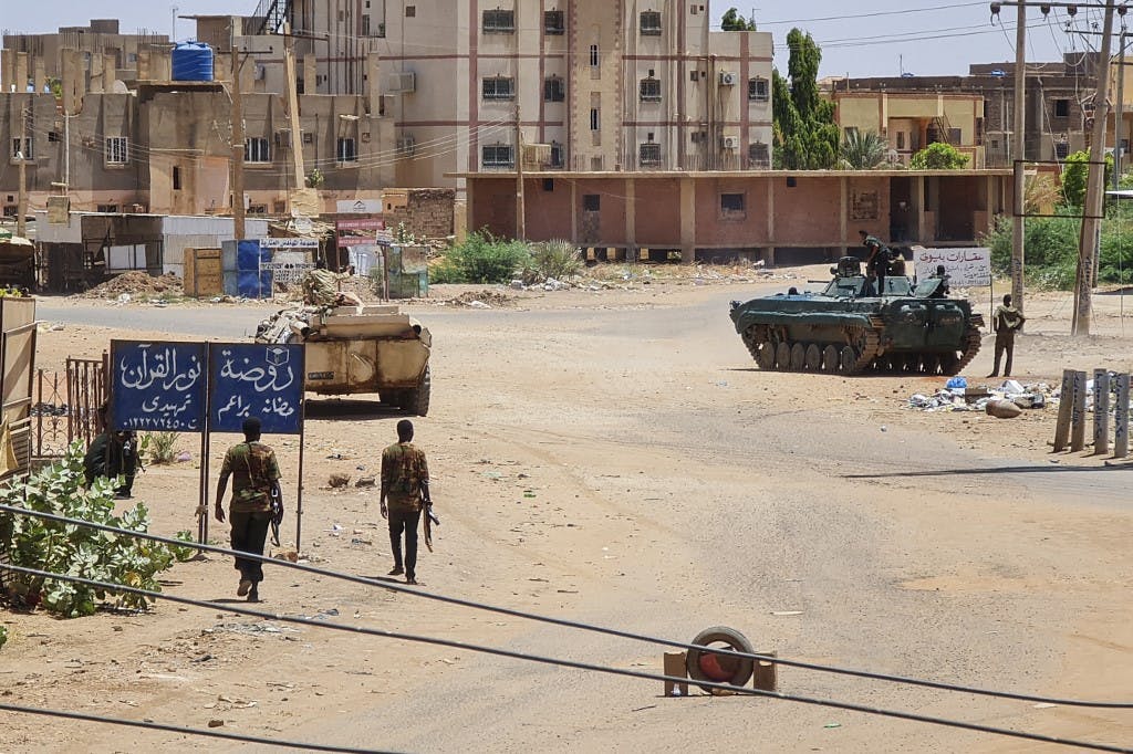سربازان ارتش سودان در ۶ مه ۲۰۲۳ در نزدیکی خودروهای زرهی مستقر در خیابانی در جنوب خارطوم در میان نبردهای مداوم علیه نیروهای پشتیبانی سریع شبه نظامی قدم می‌زنند. - حملات هوایی در ۶ می پایتخت سودان را هدف قرار داد. درگیری‌ها تنها چند ساعت قبل از اینکه طرف‌های متخاصم قرار است برای اولین گفتگوهای مستقیم خود در عربستان سعودی با یکدیگر دیدار کنند، وارد هفته چهارم شد. (عکس از خبرگزاری فرانسه)