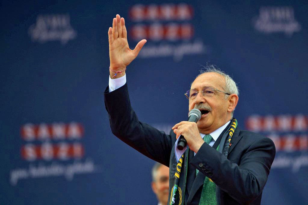 کمال قلیچداراوغلو، نامزد انتخابات ریاست‌ جمهوری ترکیه در حال سخنرانی پشت میکروفون دست خود را بلند کرده است.