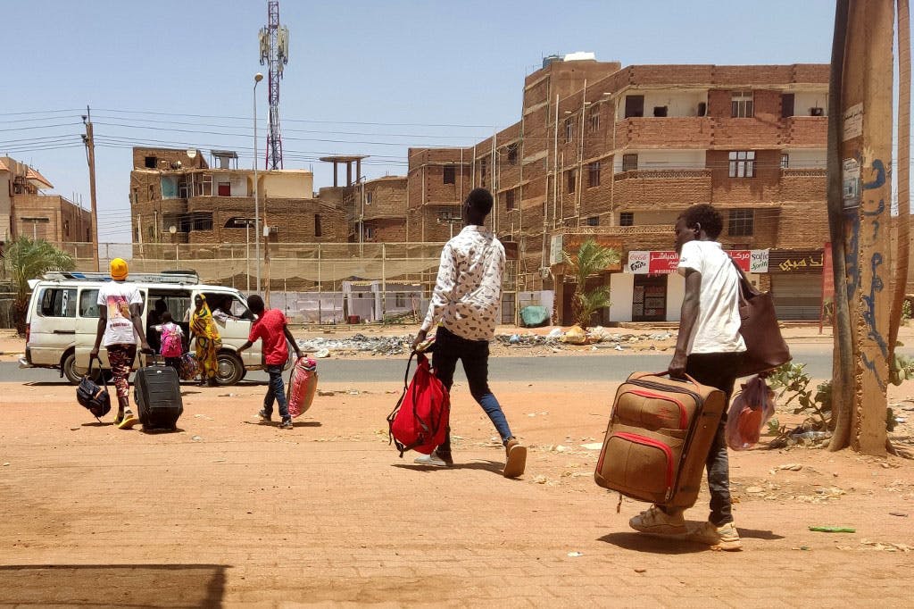 چند تن از ساکنان خارطوم، پایتخت سودان در حالی‌که چمدان‌ها و وسایل خود را در دست دارند به سمت مینی‌بوسی می‌روند تا سوار آن شوند و شهر را از بیم جنگ ترک کنند.