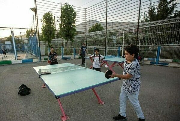 نوجوانان در حال بازی تنیس روی میز در پارکی در ایران