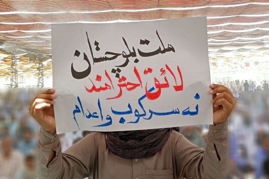 یکی از نمازگزاران بلوچ کاغذی که به بر آن نوشته شده «ملت بلوچ لایق احرامند نه سرکوب و اعدام« در دست دارد.