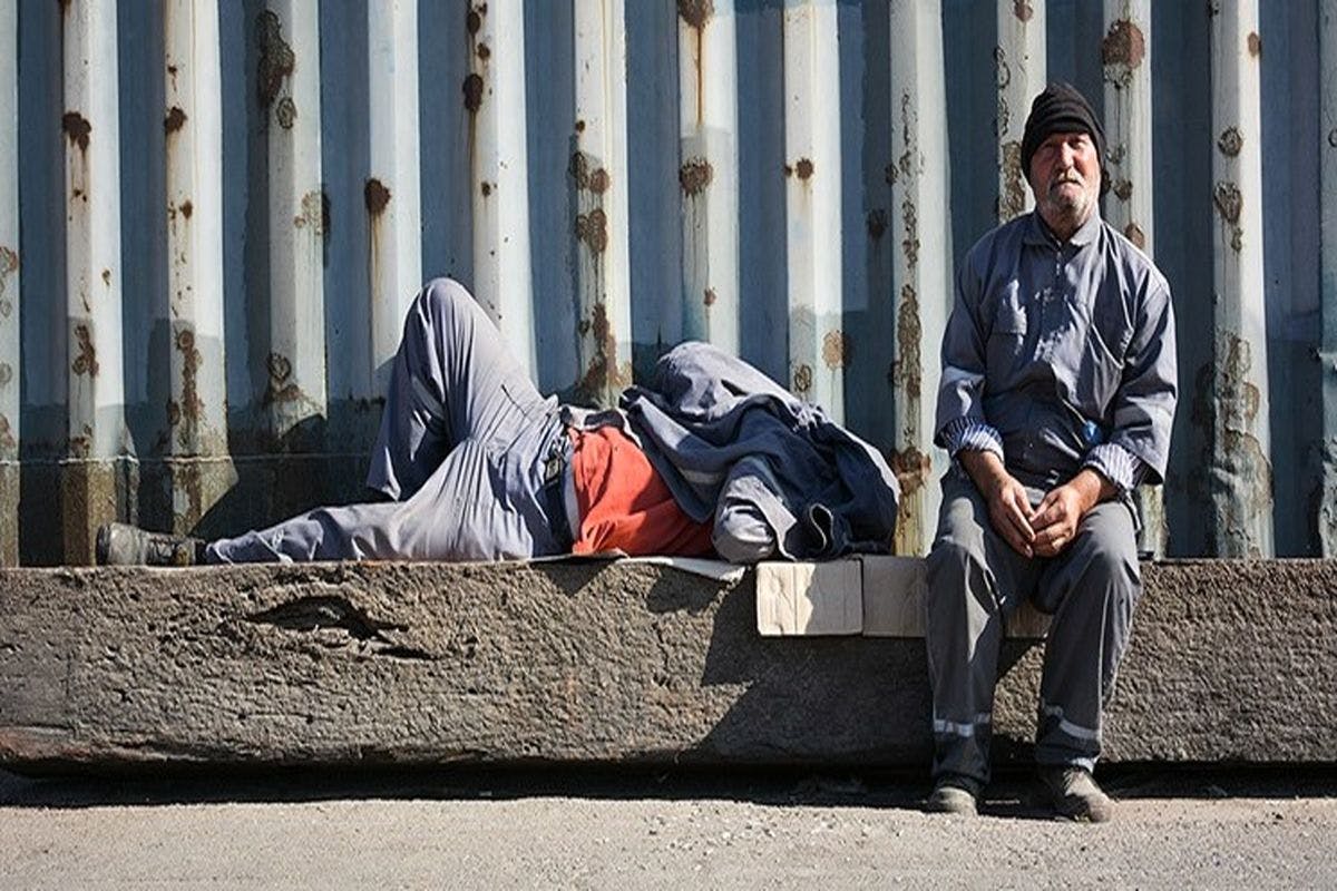 دو کارگر در کنار خیابان. یکی خسته از کار دراز کشیده دیگری خیره به دوربین. مزدبگیران سال دشوارتری خواهند داشت.