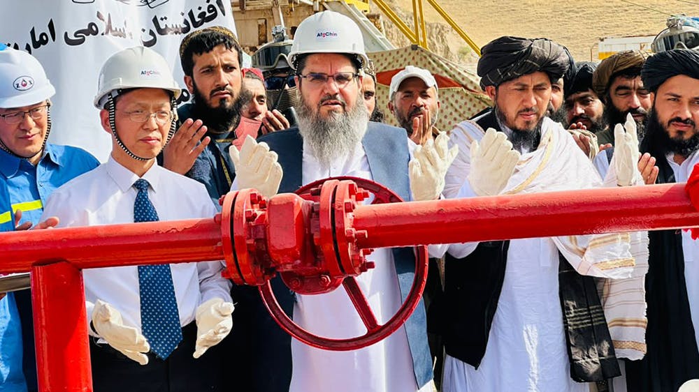 مقامات طالبان و سرمایه‌گذار چینی در حال دعا به هنگام آغاز استخراج یک چاه نفت