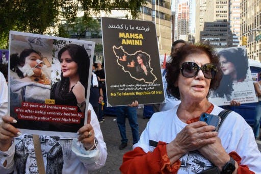 عکس تزئینی: تظاهرات مردمی روبروی ساختمان سازمان ملل در شهر نیویورک در اعتراض به قتل حکومتی مهسا امینی و زنی معترض که موبایل خود را به آغوش کشیده است.