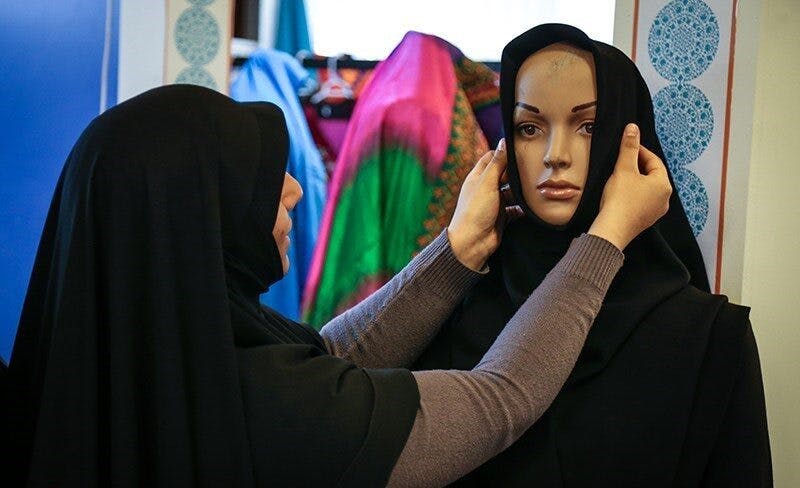 یک زن محجبه در حال «درست‌کردن» مقنعه بر سر یک مانکن - عکس از ناصر جعفری/باشگاه خبرنگاران پویا