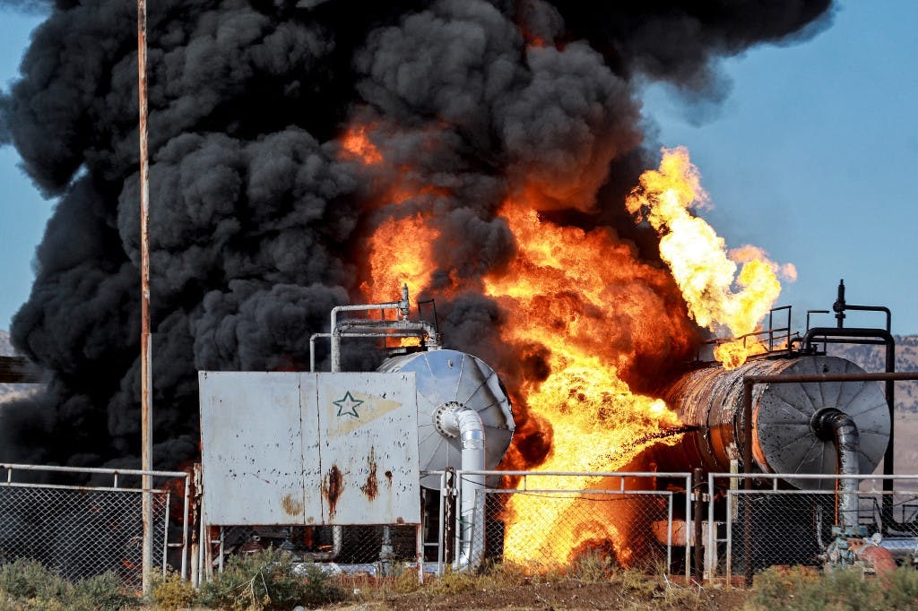 شعله‌های آتش و دود از یک مرکز ذخیره نفت در شمال سوریه که ترکیه به آن حمله کرده است. عکس: Delil SOULEIMAN / AFP