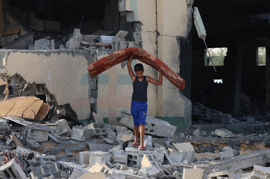 ۸ اکتبر ۲۰۲۳، خان یونس در جنوب نوار غزه. کودکی فلسطینی وسایل زندگی را از خانه‌ای ویران خارج می‌کند.