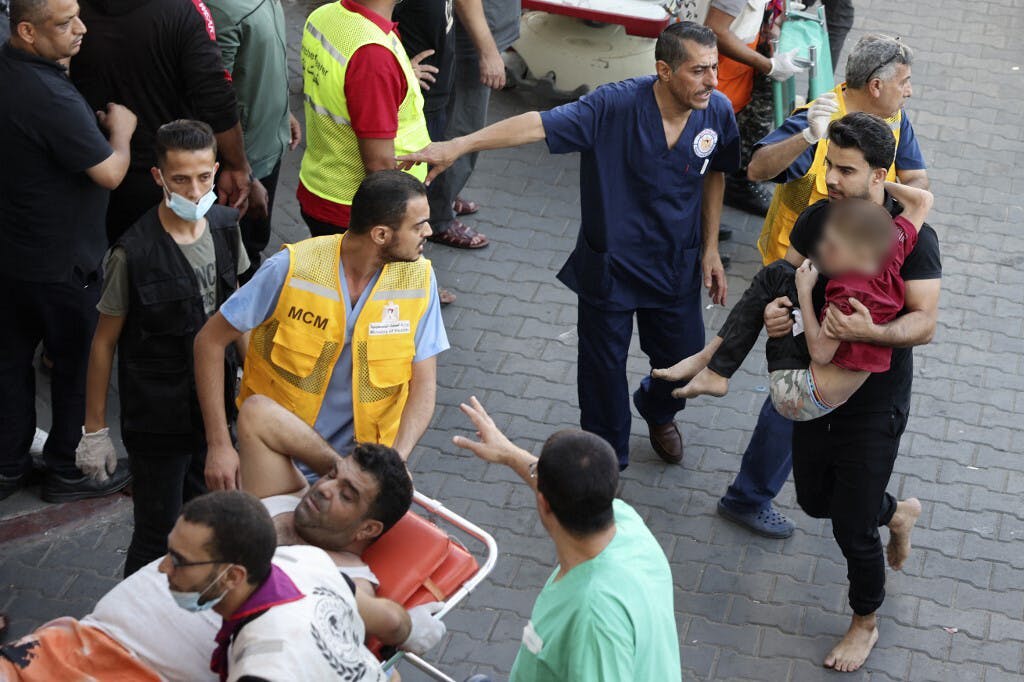 "مردی در پی حملات اسرائیل به شهر غزه در ۱۰ اکتبر ۲۰۲۳، کودکی مجروح را به بیمارستان الشفا منتقل می‌کند. عکس حمد عبد/ خبرگزاری فرانسه"