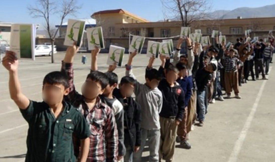 گروهی کودک در یک مدرسه و کتاب آموزش به زبان مادری در دسترس