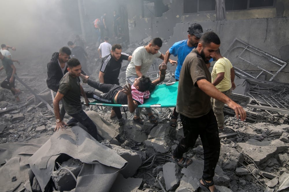 گروهی برانکارد حامل یک مجروح بر اثر بمباران اسرائیل را حمل می‌کنند.