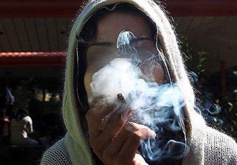 تصویری از یک زن در حال سیگار کشیدن. دود تمام صورت او را پوشانده است.
