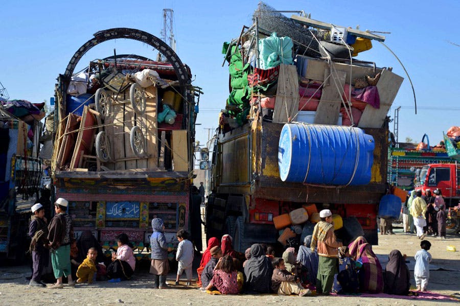در تصویر چندین کامیون با بارهای زیاد از وسایل پناهجویان افغانستانی دیده می‌شود که در کنار آن‌ها خانواده‌ها و کودکان افغانستانی روی زمین در انتظار نشسته‌اند.