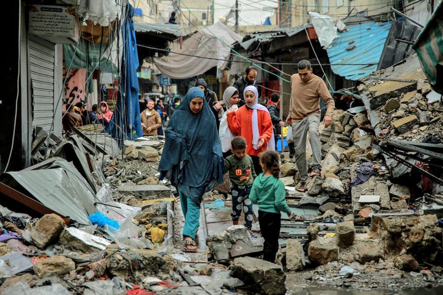 چند زن و کودک فلسطینی در میان آوار ساختمان‌های ویران‌شده از بمباران اسرائیل از بازار شهر غزه بازمی‌گردند.