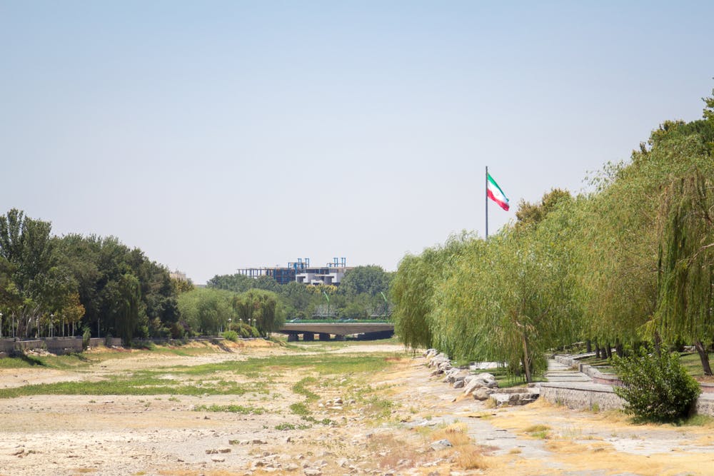 تصویر از شاتر استاک: پرچم جمهوری اسلامی در کنار رودخانه‌ای کامل خشکیده