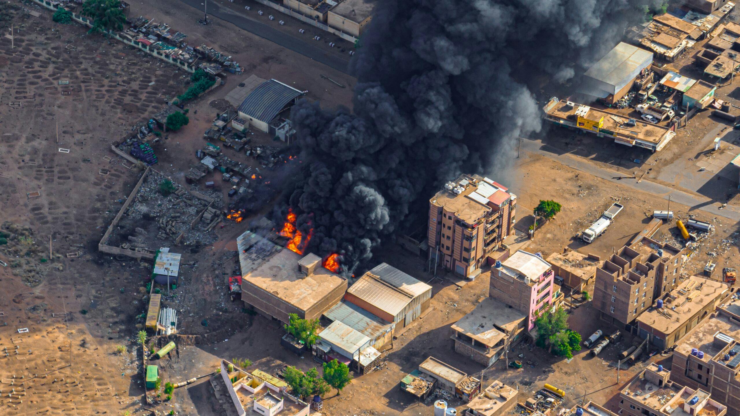 تصویری هوایی از شهر که در آن ساختمانی به آتش کشیده شده و دودی سیاه آسمان را گرفته است
