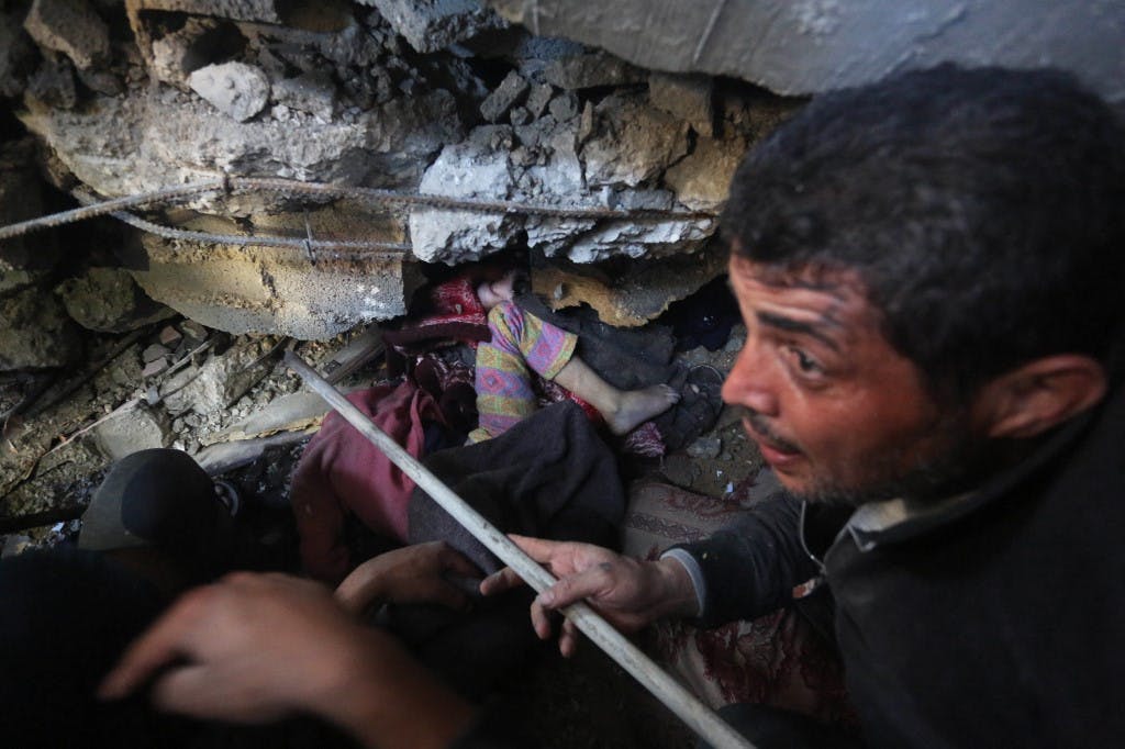 محتوای خشونت‌آمیز و ناراحت‌کننده/ فلسطینی‌ها در پی حمله اسرائیل به منطقه زویدا در مرکز نوار غزه در ۳۰ دسامبر ۲۰۲۳ تلاش می‌کنند جسد یک کودک را از زیر خاک بیرون بیاورند. (عکس از خبرگزاری فرانسه)