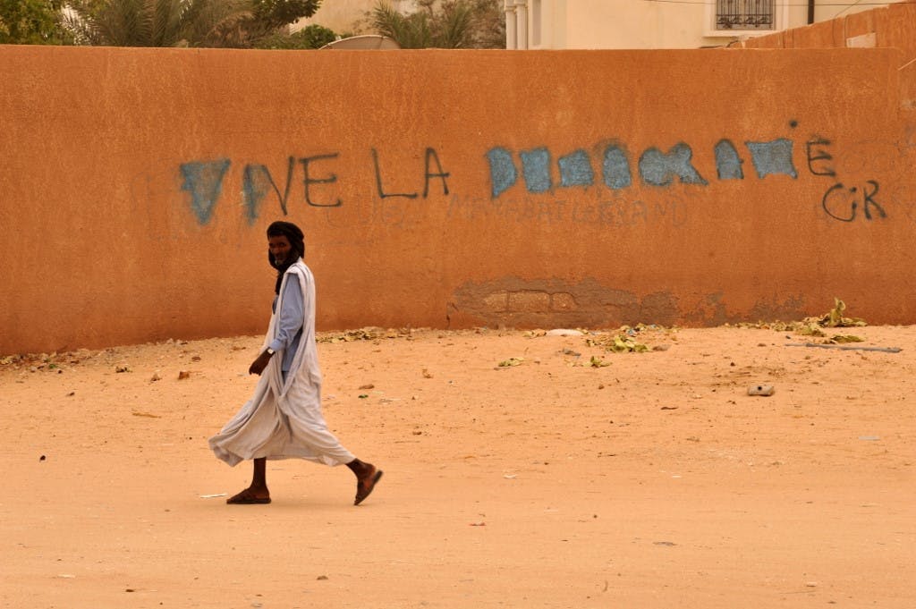 یک شهروند موریتانیایی از کنار دیواری با گرافیتی می‌گذرد با این پیام: «زنده باد دموکراسی» (عکس: خبرگزاری فرانسه)