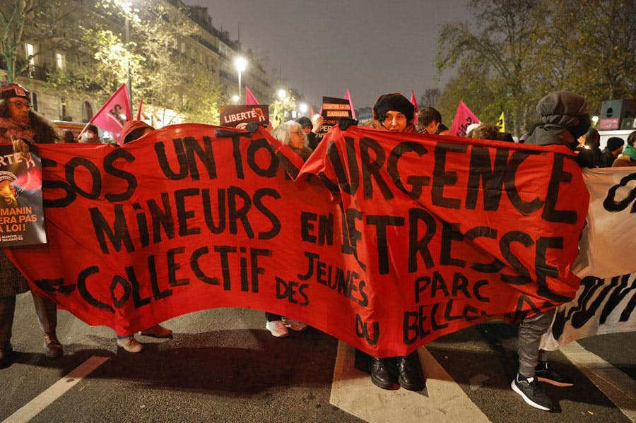 معترضان به لایحه بحث برانگیز مهاجرت در پاریس پلاکاردی در دست دارند و علیه این لایحه شعار سر داده‌اند.