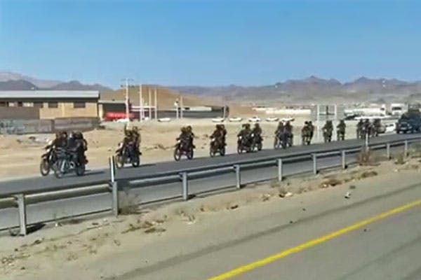 در تصویر چندین موتورسیکلت که بر روی هر کدام دو مأمور امنیتی جمهوری اسلامی نشسته‌اند و به‌دنبال آن‌ها خودروهای نظامی، در یک اتوبان پشت سر هم در حال حرکت دیده می‌شوند.