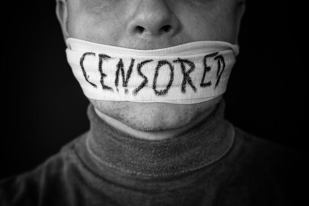 تصویر صورت مردی که دهانش با پارچه بسته شده و برپارچهنوشته شده است سانسور