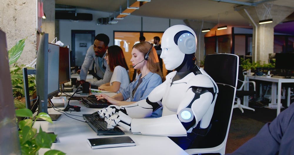 تصویر تزئینی از شاتر استاک یک ربات را در یک اداره در حال کار در کنار انسان‌ها نشان می‌دهد.
