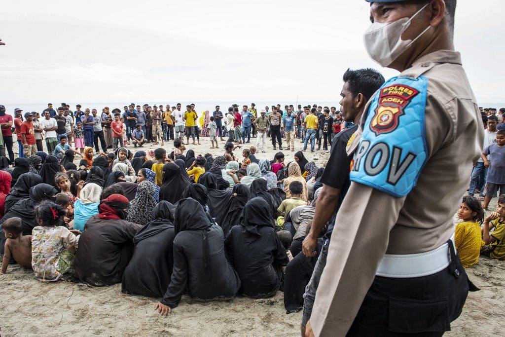 جمعی از پناهجویان روهینگیا اعم از بزرگسال و کودک در ساحل کالی در لاوئونگ در استان آچه اندونزی- آن‌ها پس از رسیدن به ساحل روی زمین نشسته‌اند. ۱۴ نوامبر ۲۰۲۳ (عکس از Jon S / AFP)