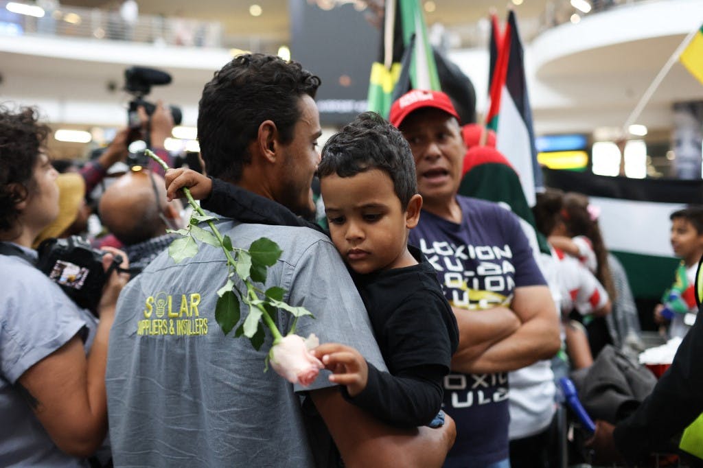 یک کودک اهل آفریقای جنوبی با یک رز سفید در آغوش پدرش در جمع معترضان در مقابل دادگاه لاهه