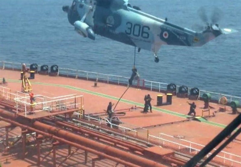 تعدادی نیروی نظامی از یک هلی‌کوپتر در حال پیاده شدن روی عرشه یک کشتی