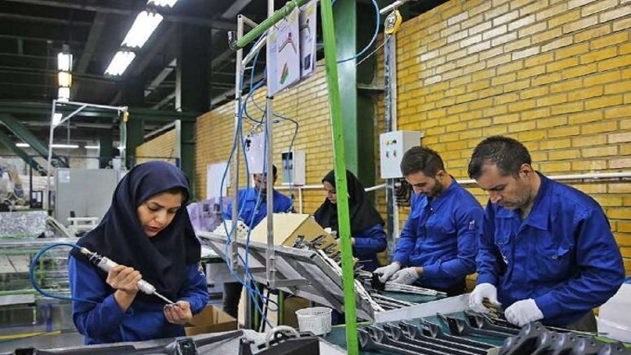 تصویری از تعدادی زن و مرد که در کنار هم در یک کارخانه در حال کارند.