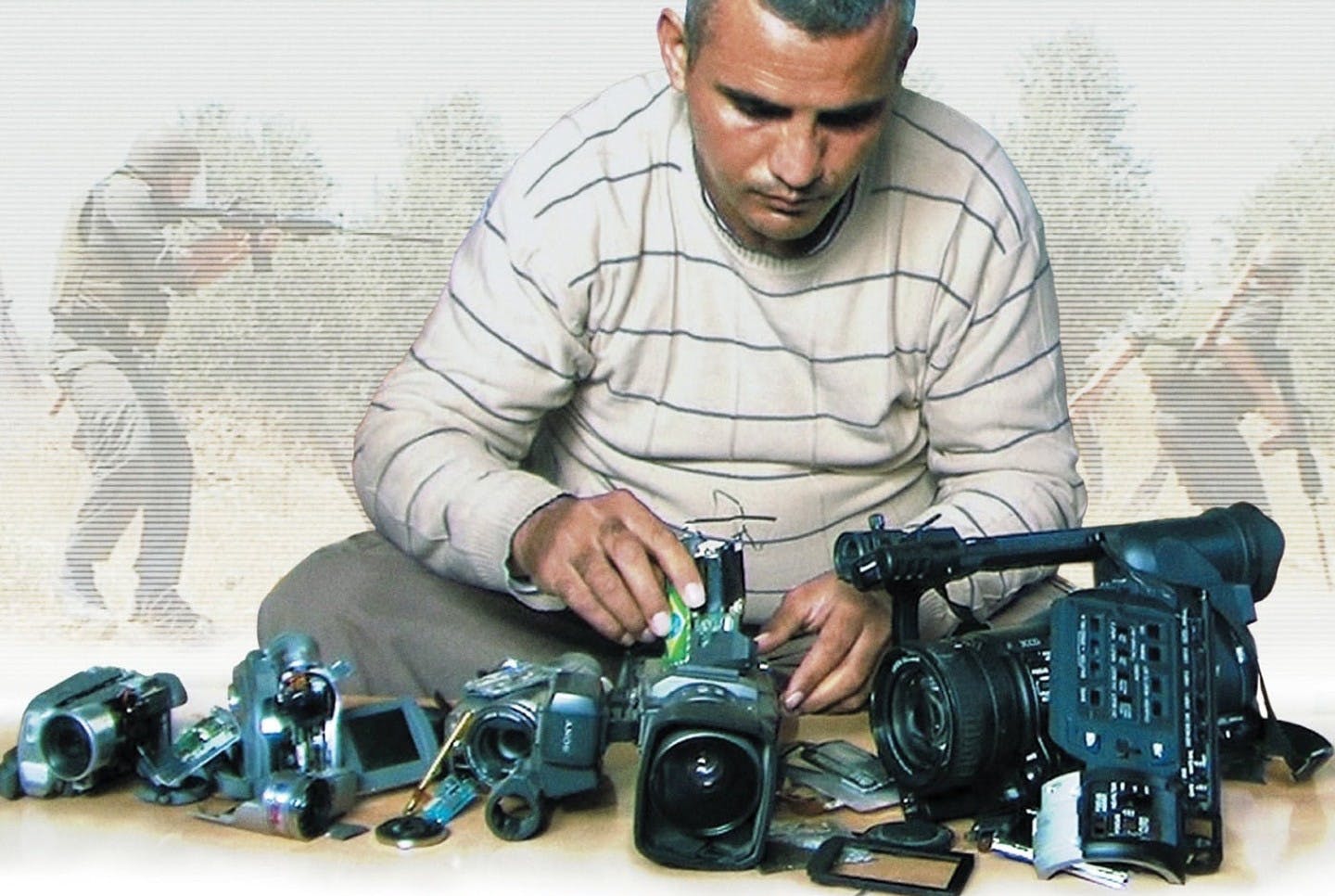 تصویر مردی با تعدادی دوربین عکاسی و در پس زمینه تصویر جنگ