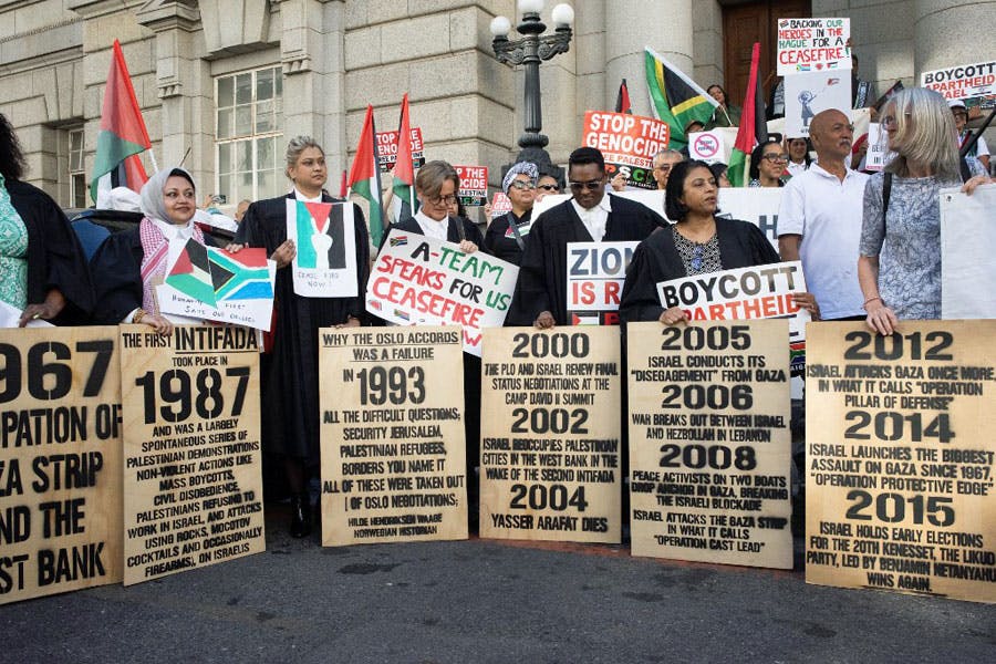در تصویر گروهی از وکلای آفریقای جنوبی و مردم این کشور پلاکاردهایی در مورد «نسل‌کشی» و حمایت از مردم فلسطین در دست دارند.