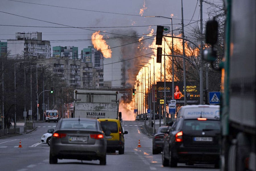تصویر، خیابانی در کی‌یف، پایتخت اوکراین را نشان می‌دهد. کمی دورتر آتش مهیبی در پیاده‌روی خیابان شعله‌ور شده و خودروها ایستاده‌اند.
