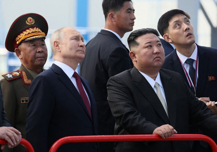 در تصویر ولادیمیر پوتین، رئیس جمهوری روسیه و رهبر کره شمالی، کیم جونگ اون به همراه گروهی از نظامیان و محافظان در بازدید از فضاپیمای Vostochny در منطقه آمور روسیه به آسمان نگاه می‌کنند.
