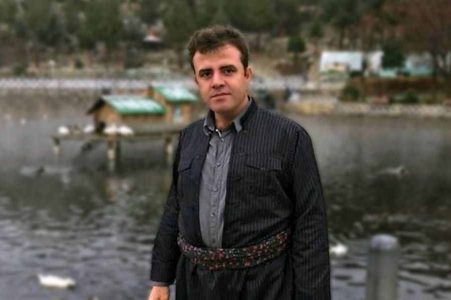 در تصویر یوسف احمدی با لباس کُردی در یک پارک دیده می‌شود.